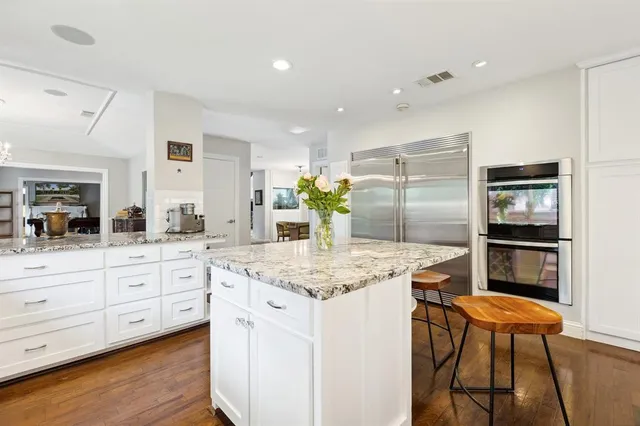 a kitchen with stainless steel appliances kitchen island granite countertop a table chairs sink and cabinets