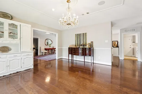 a view of a livingroom with furniture wooden floor a chandelier and windows