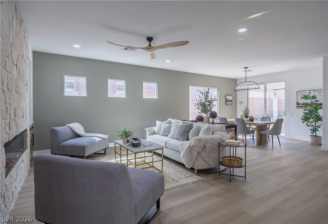 10982 Village Ridge Lane Las Vegas, NV 89135 - Photo 6 of 12 Natural light illuminates this spacious great room, featuring a striking stone fireplace and durable wood flooring.