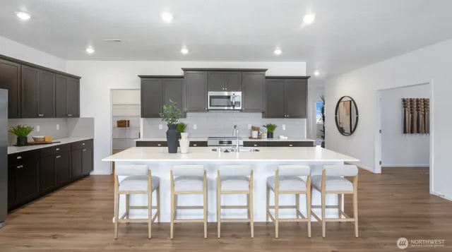 a kitchen with stainless steel appliances granite countertop a dining table chairs and stove top oven