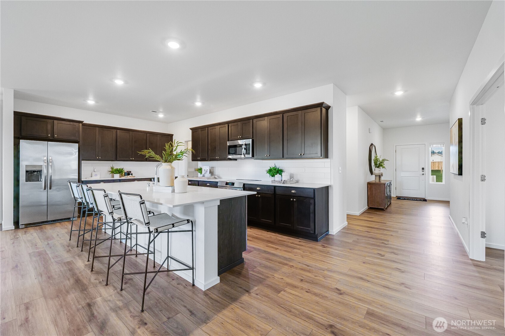132 Moonshadow Lane Sequim, WA 98382 - Photo 2 of 28 a kitchen with stainless steel appliances kitchen island granite countertop a stove top oven a sink dishwasher a refrigerator and a dining table with wooden floor