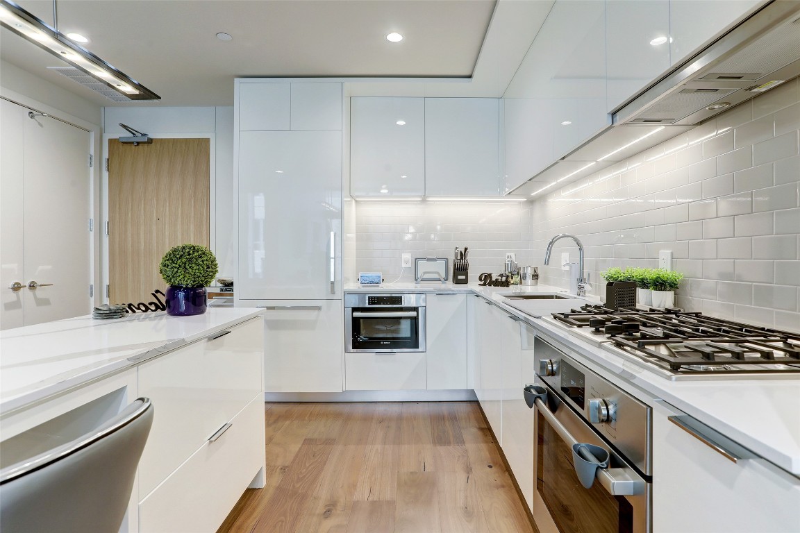 44 East Avenue, Unit 1502 Austin, TX 78701 - Photo 4 of 16 Kitchen with modern cabinets, white cabinets, stainless steel appliances, range hood, and recessed lighting