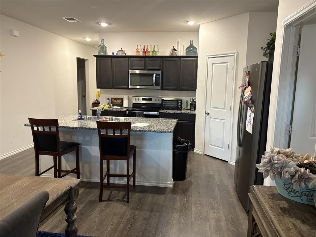 3124 Patton Lane Forney, TX 75126 - Photo 8 of 19 a kitchen with stainless steel appliances a dining table chairs stove refrigerator and microwave