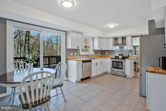 a kitchen with granite countertop a stove a sink a dining table and chairs