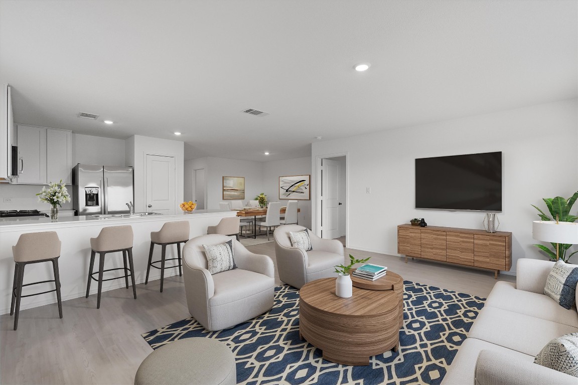 a living room with furniture kitchen view and a flat screen tv