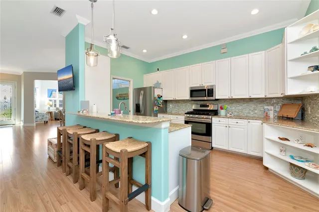 a kitchen with stainless steel appliances granite countertop a stove top oven a sink dishwasher a dining table and chairs with wooden floor