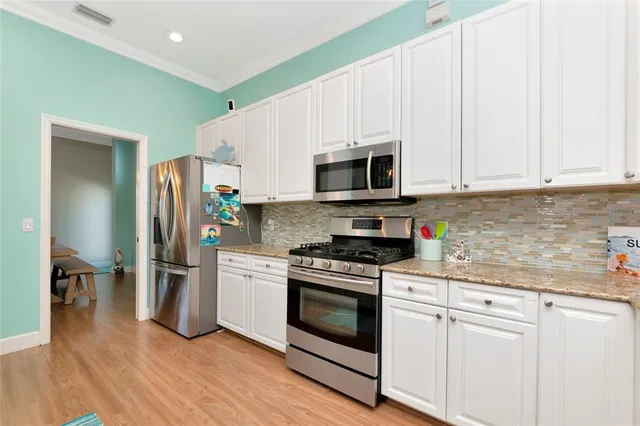 a kitchen with stainless steel appliances white cabinets and a stove top oven