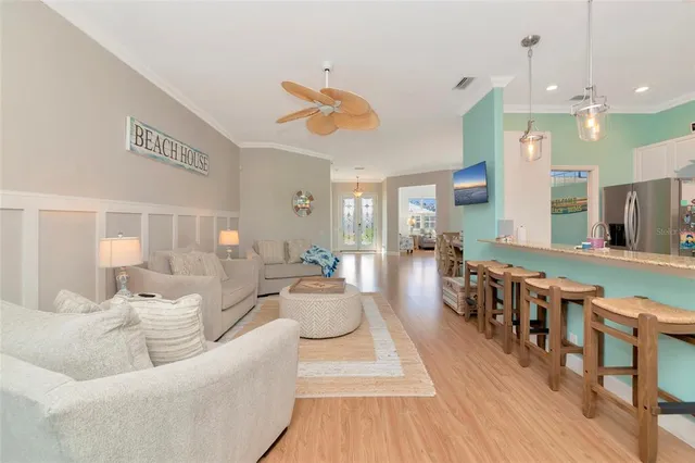 a living room with furniture kitchen view and a wooden floor