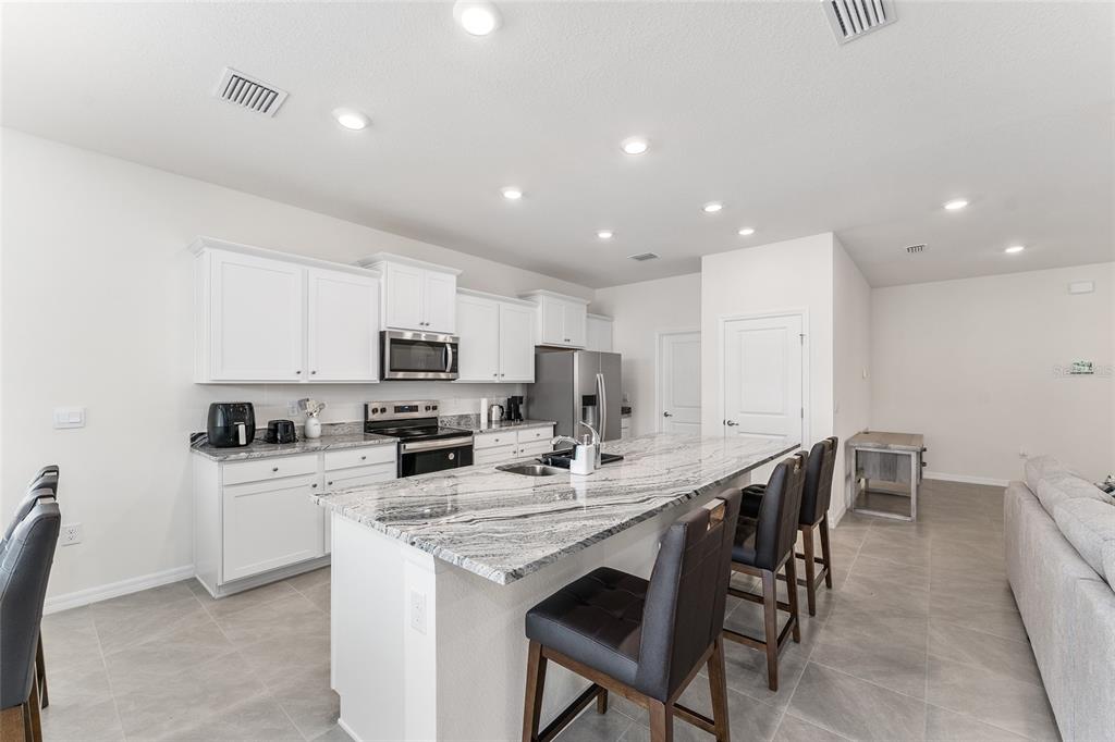 4098 Northwest 48th Terrace Ocala, FL 34482 - Photo 16 of 58 a kitchen with stainless steel appliances kitchen island granite countertop a stove a sink a dining table and chairs
