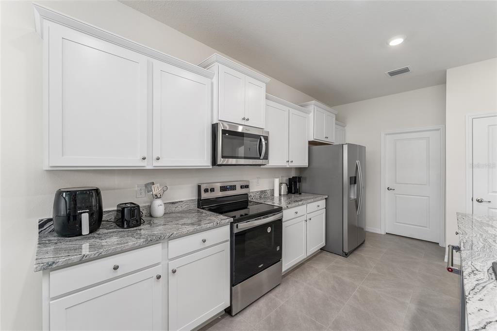 4098 Northwest 48th Terrace Ocala, FL 34482 - Photo 21 of 58 a kitchen with stainless steel appliances granite countertop white cabinets a refrigerator a sink a stove a microwave and wooden cabinets