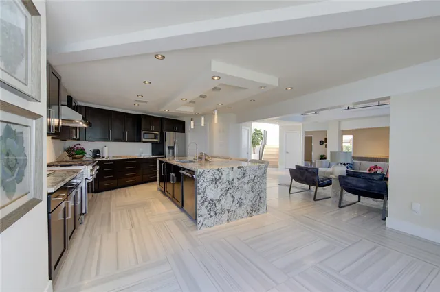 a dining room with stainless steel appliances a dining table chairs wooden floor and a rug