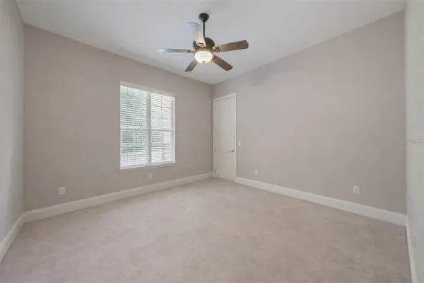 an empty room with windows and fan