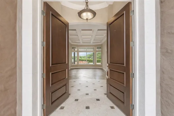 a view of a hallway with chandelier and glass door