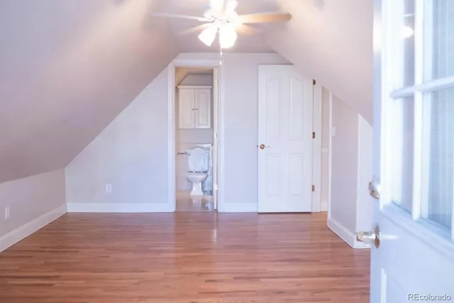 a view of an empty room with wooden floor and fan