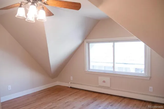 an empty room with wooden floor chandelier fan and windows