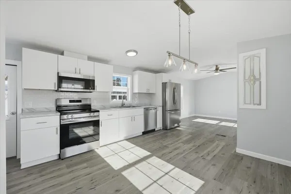 a large kitchen with cabinets a sink and stainless steel appliances