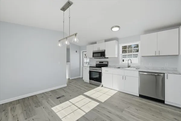 a kitchen with granite countertop a stove cabinets and wooden floor