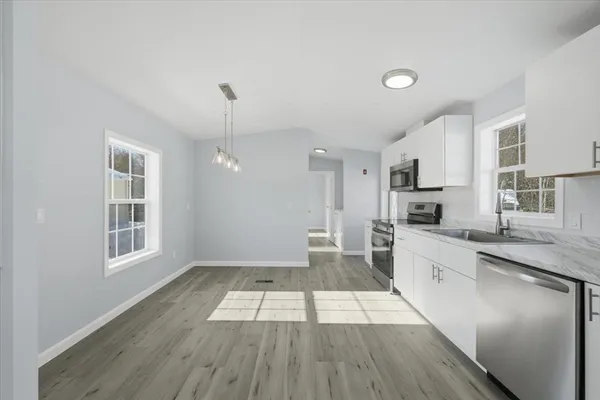 a large kitchen with cabinets wooden floor and stainless steel appliances