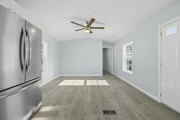 an empty room with wooden floor a ceiling fan and windows