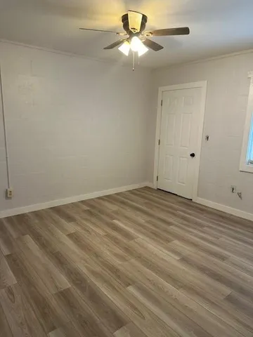 an empty room with wooden floor fan and windows