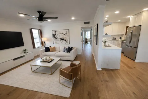 a living room with furniture a flat screen tv and a refrigerator