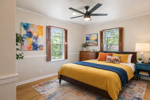 a bedroom with a large bed painting on the wall and a window