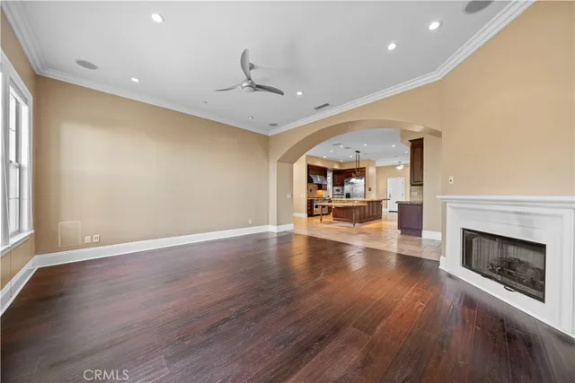 an empty room with wooden floor fireplace and windows