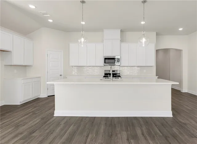 a white kitchen with wooden floors stainless steel appliances and white cabinets