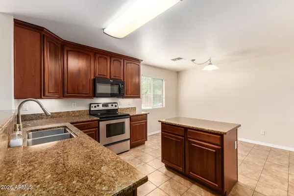 a kitchen with stainless steel appliances granite countertop a stove a sink and a microwave