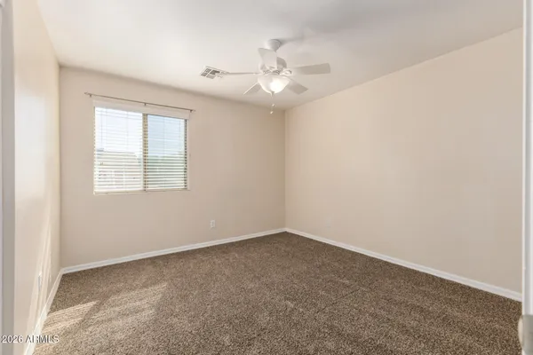 an empty room with a chandelier fan and windows