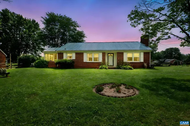 a view of house with a big yard and potted plants and trees
