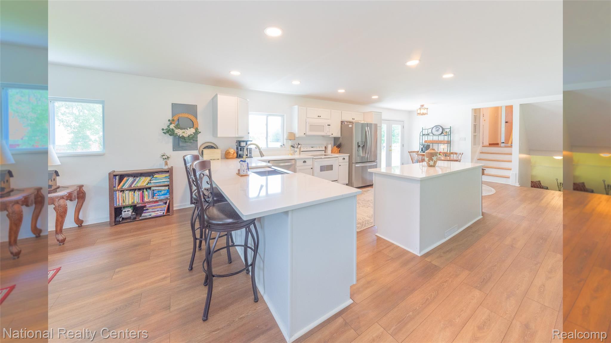 58191 8 Mile Road Northville, MI 48167 - Photo 29 of 57 Open-concept kitchen with wood-finish flooring, white cabinetry, recessed lighting, and dual islands featuring white countertops
