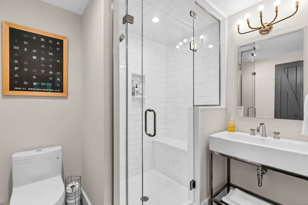 a bathroom with a sink a toilet a shower and a mirror