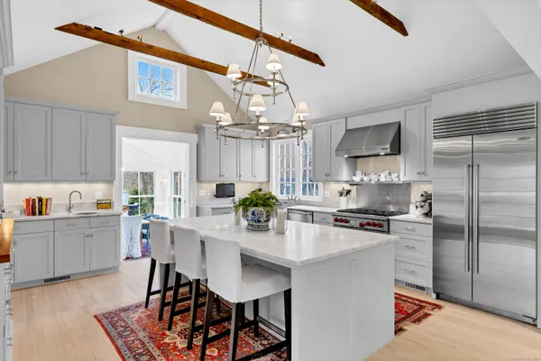 a kitchen with stainless steel appliances a dining table chairs refrigerator and stove