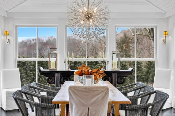 a dining room with furniture a chandelier and a large window