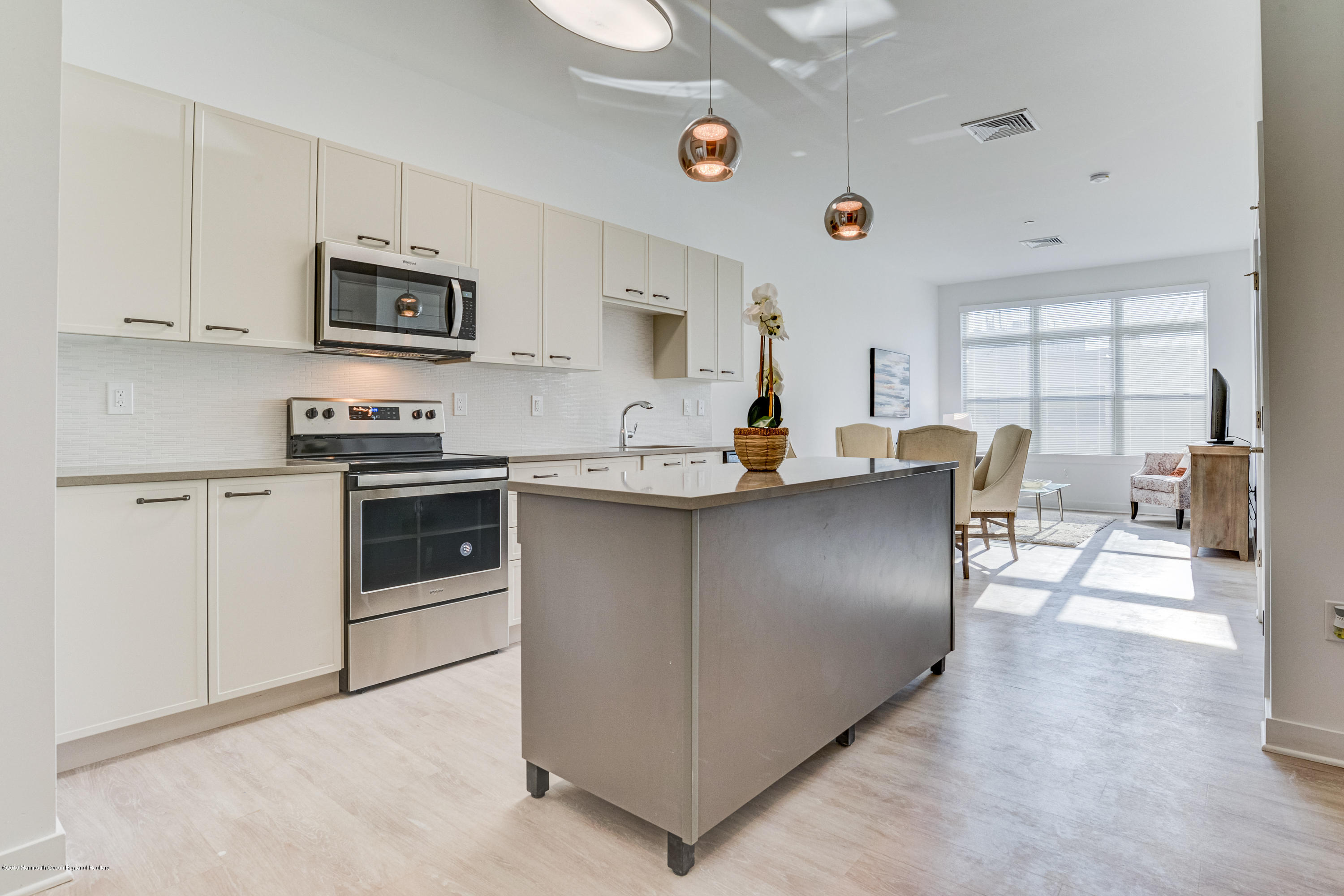 55 West Front Street, Unit 306 Red Bank, NJ 07701 - Photo 7 of 24 a kitchen with stainless steel appliances granite countertop a stove top oven a sink a dining table and chairs with white cabinets