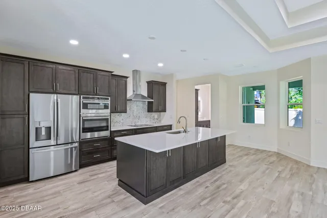 a large kitchen with kitchen island a large counter top and stainless steel appliances