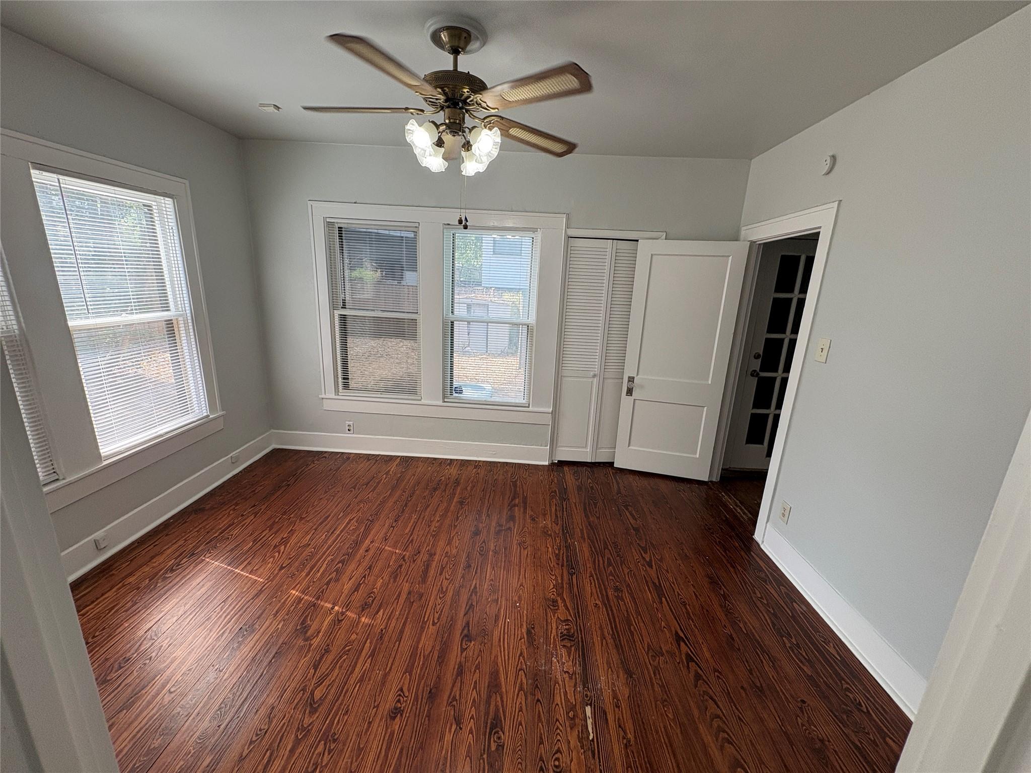 915 West 29th Street Austin, TX 78705 - Photo 8 of 20 Spacious room featuring wood-finish flooring, multiple windows, a ceiling fan with integrated lighting, and a louvered bi-fold closet door