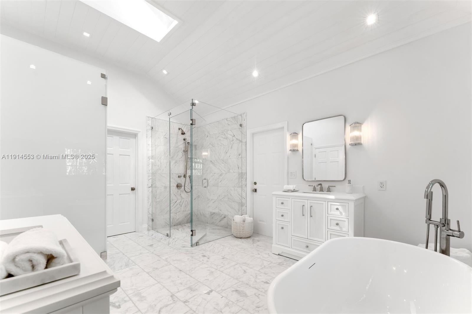 6675 Roxbury Lane Miami Beach, FL 33141 - Photo 38 of 40 a large white room with a mirror a sink and glass door shower