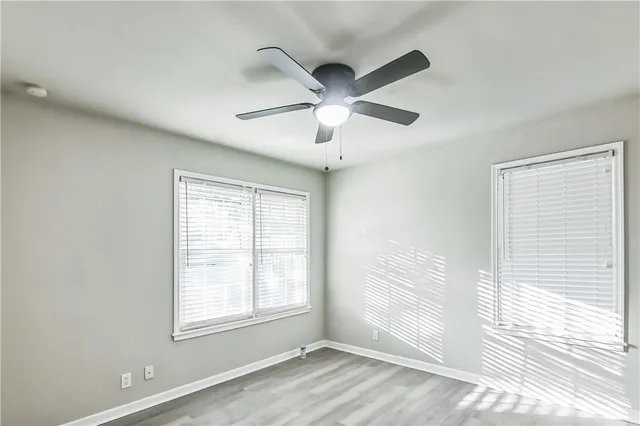 a view of an empty room with a window and wooden floor