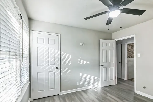 a view of a hallway with wooden floor and cabinet with a ceiling fan
