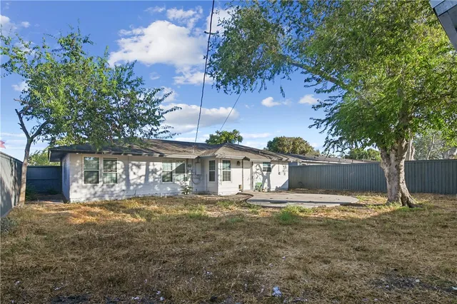 a view of house with yard and trees in the background