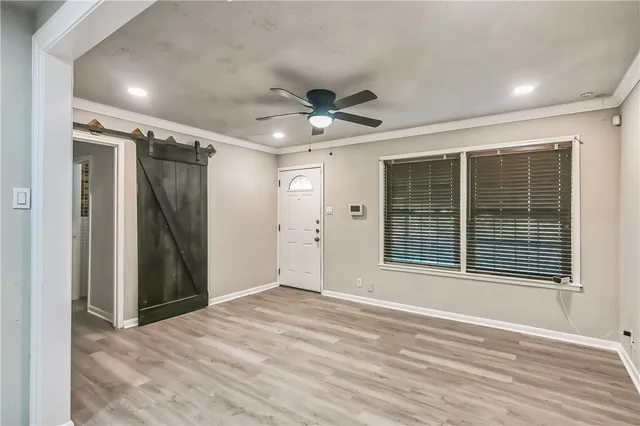 a view of an empty room with a window and a kitchen