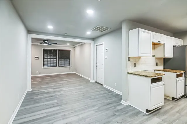 a kitchen with granite countertop a stove cabinets and wooden floor