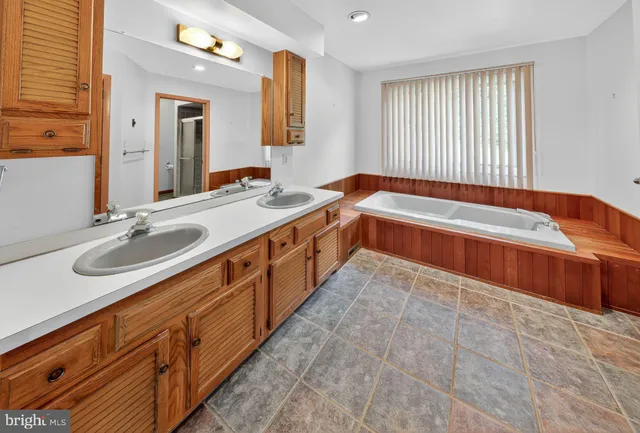 a spacious bathroom with a sink double vanity mirror and a bathtub