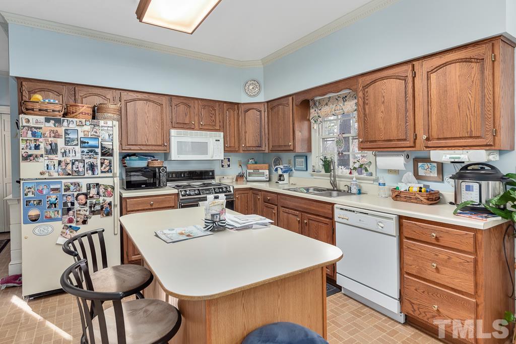 2416 Basil Drive Raleigh, NC 27612 - Photo 12 of 26 a kitchen with a stove a sink and a refrigerator