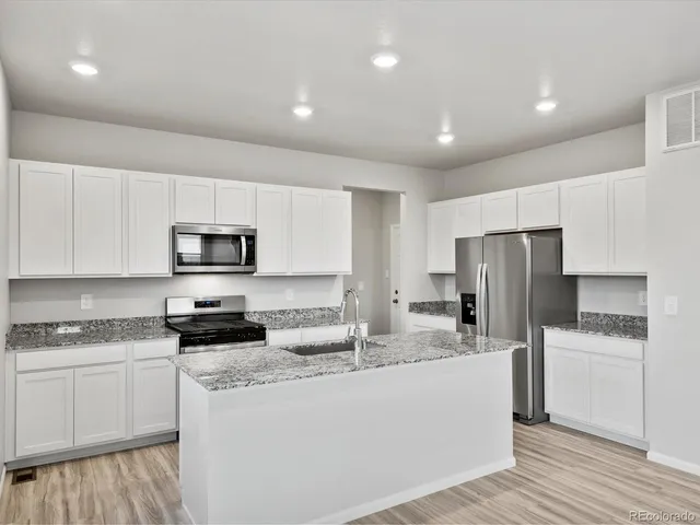 a kitchen with stainless steel appliances a refrigerator sink and white cabinets