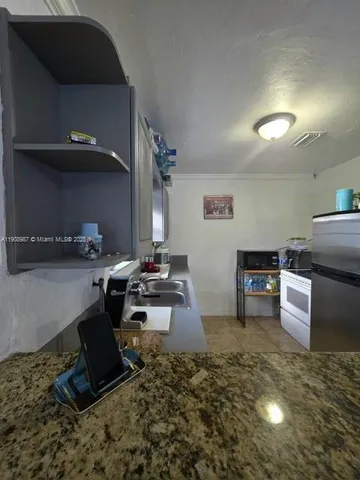 a kitchen with kitchen island granite countertop a sink appliances and cabinets