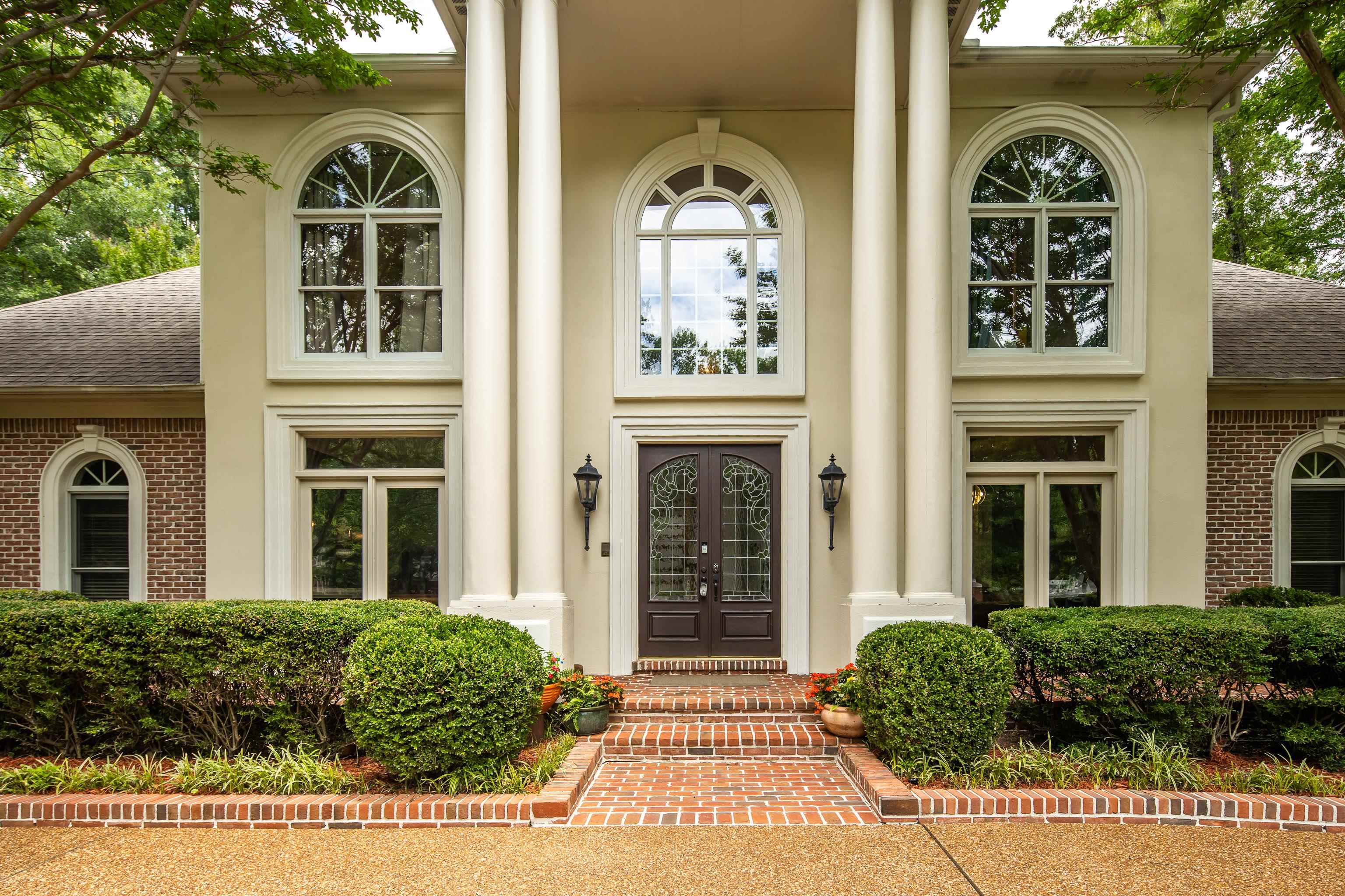 350 Bluff Ridge Cove Memphis, TN 38018 - Photo 9 of 37 Stucco and brick facade featuring a double-door entry with decorative glass, flanked by large arched windows and substantial architectural columns