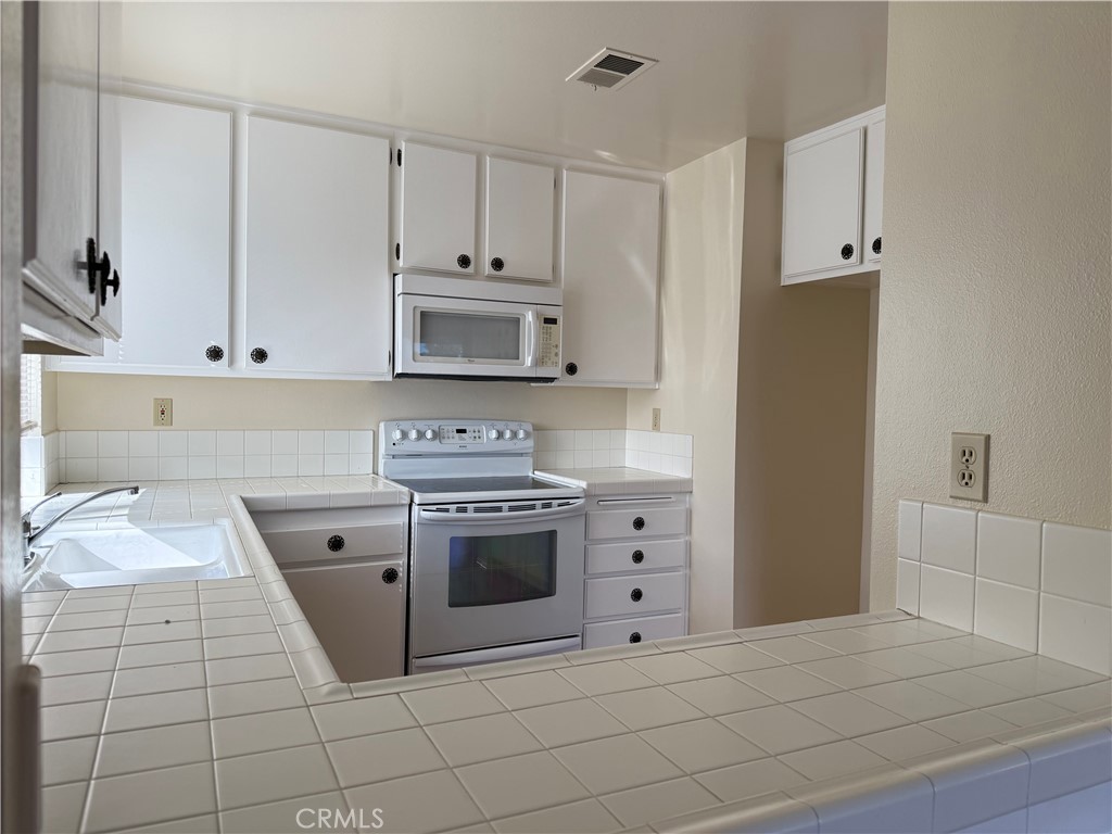 19547 Rinaldi Street, Unit 27 Porter Ranch, CA 91326 - Photo 18 of 20 a kitchen with white cabinets and appliances